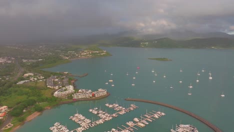 sunrise morning rain shower cannonvale port airlie beach bay lagoon coral sea marina aerial drone sunrise heart of great barrier reef whitsundays whitehaven jetty yachts backwards motion