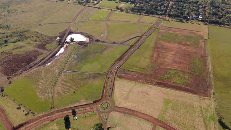 high aerial of car driving on rural dirt road through green countryside