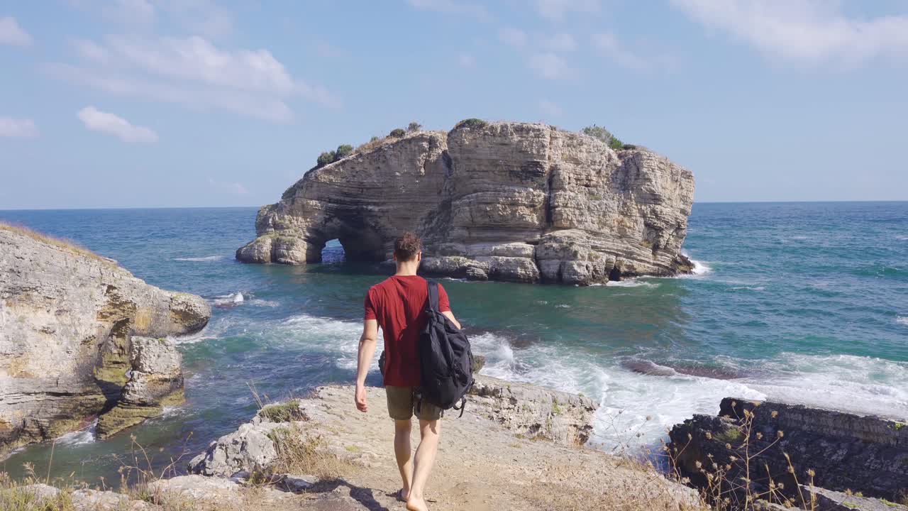 un joven aventurero caminando por los acantilados del mar.