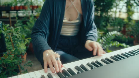 female musician playing keyboard in greenhouse filled with lush plants