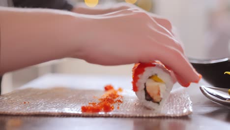 hacer sushi en la cocina de casa. manos de mujer enrollando sushi casero.