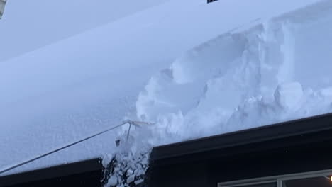 rakng snow off of a roof in winter