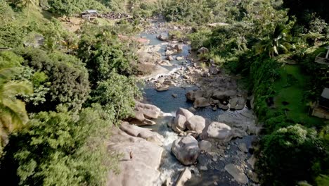 Toma-Aérea-De-Drones-En-Cascada-Rodeada-De-Casas,-árboles-Y-Rocas