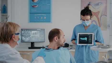 stomatological team pointing at denture radiography on tablet