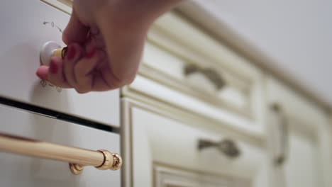 Woman-hand-turning-knob-on-gas-stove-on-modern-kitchen