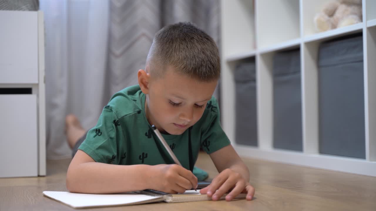 Boy draws while watching a lesson on the phone