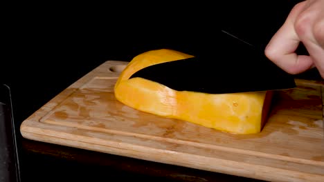 vista bloqueada de calabaza butternut cortada en rodajas sobre una tabla de cortar de madera