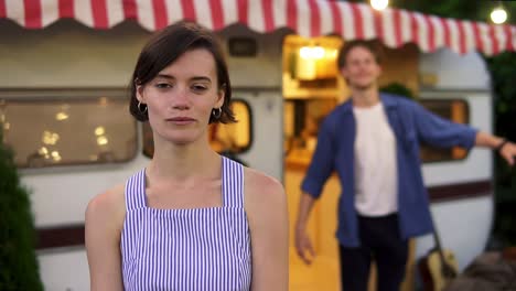 Happy-Cheerful-Couple-Portrait-Of-A-Pretty,-Brunette-Girl-Smiling-At-Foreground-And-A-Man-Having-Fun-Time,-Dancing-Funny-On-Doorstep-House-On-Wheels-Outdoors