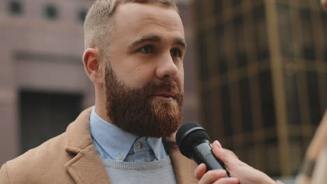 close-up view of caucasian man with beard talking and answering to female journalist in the street in autumn