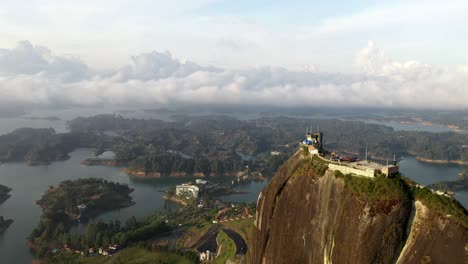 sideways dolly aerial cinematic shot of el peñol rock and reservoir during golden hour sunset at guatape colombia