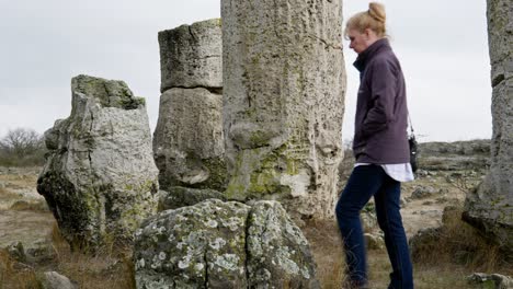 Woman-wandering-alone-in-peaceful-landscape-of-ancient-natural-rock-formations