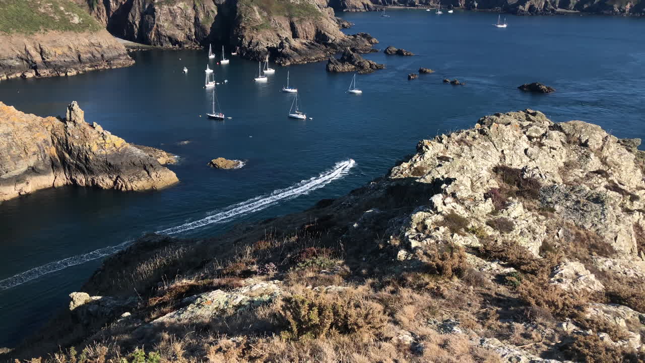 jet ski pasando por un estrecho camino de agua entre dos islas, con yates anclados en una bahía en el fondo
