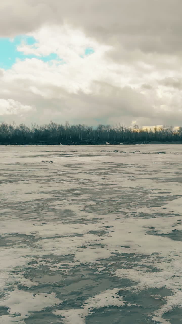 pictorial winter river covered with snow and modern bridge against wood on bank and sky with grey clouds aerial view