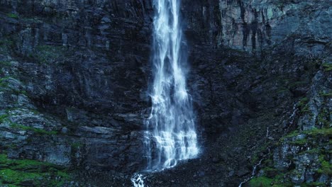 aerial backwards shot natural waterfall falling at rocky mountains