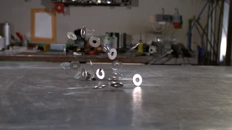 m10 washers falling in super slow motion on a metal surface in a metal shop