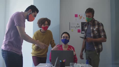 Diverse-colleagues-wearing-face-masks-working-together-in-meeting-room-at-modern-office