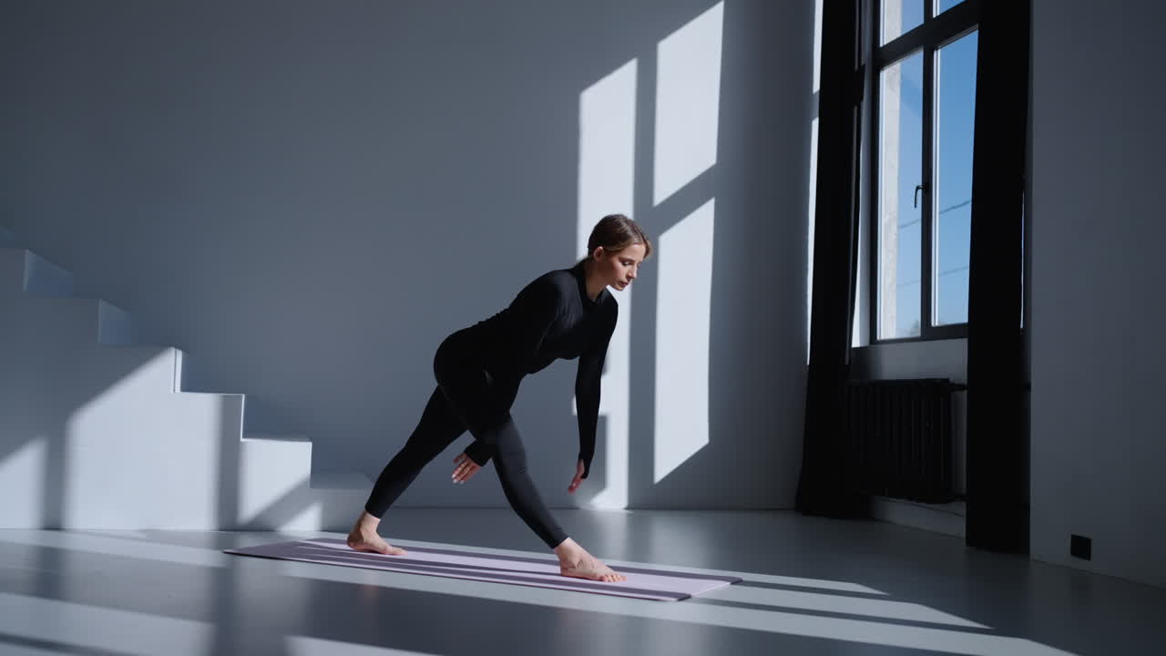 Donna che esegue una posa yoga su un tappetino in uno studio
