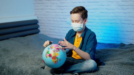 boy stays home bored by school closings due to covid pandemic. boy wearing medical face mask.