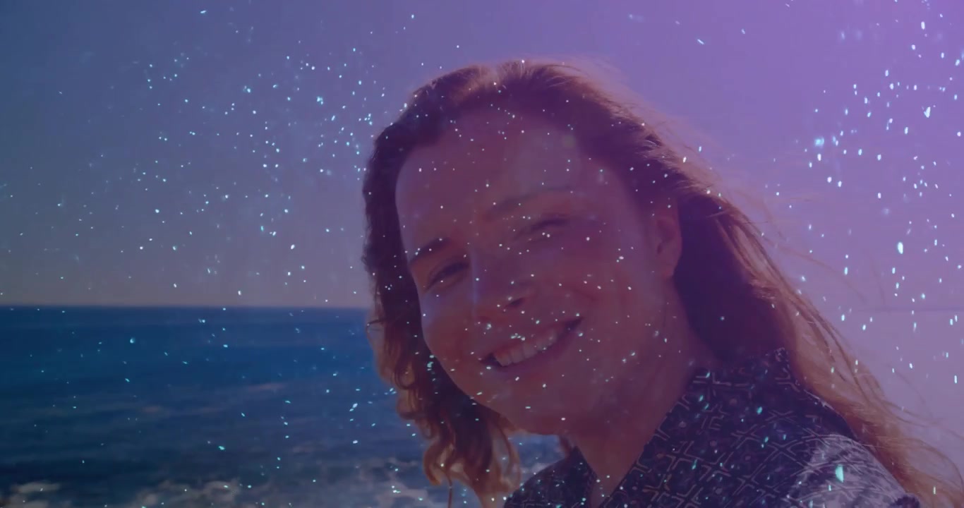 Un effetto scintillante che appare fa girare la testa di una donna verso l'oceano, evidenziando il tema della bellezza e del benessere.