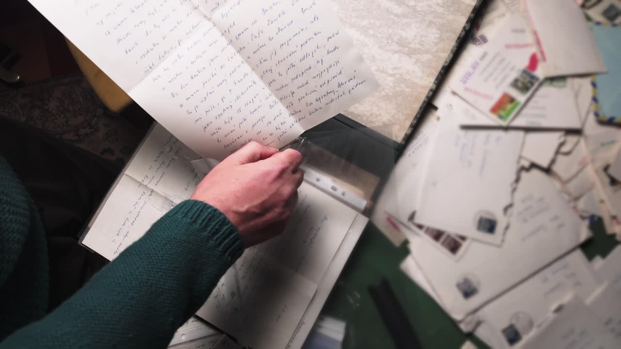 Archivist inserts personal sentimental mail letters into A4 sleeves. Overhead view