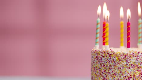 Studio-Shot-Of-Paper-Confetti-Falling-On-Birthday-Cake-Covered-With-Decorations-And-Lit-Candles