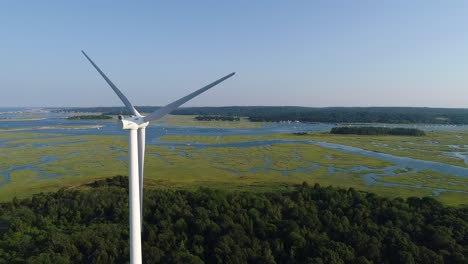 Ocean-with-a-windmill,-and-a-marsh-filmed-with-a-drone