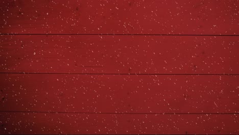 Animation-of-winter-scenery-snow-falling-against-red-wooden-boards