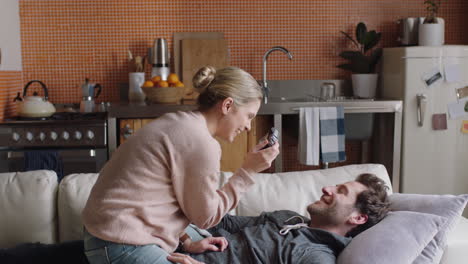 pareja joven feliz tomando fotos juntos usando la cámara divirtiéndose en casa en el sofá jugando disfrutando de una relación romántica fotografiándose el uno al otro haciendo caras