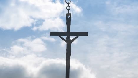 Animation-of-crucifix-hanging-on-chain-over-clouds-moving-in-blue-christmas-sky