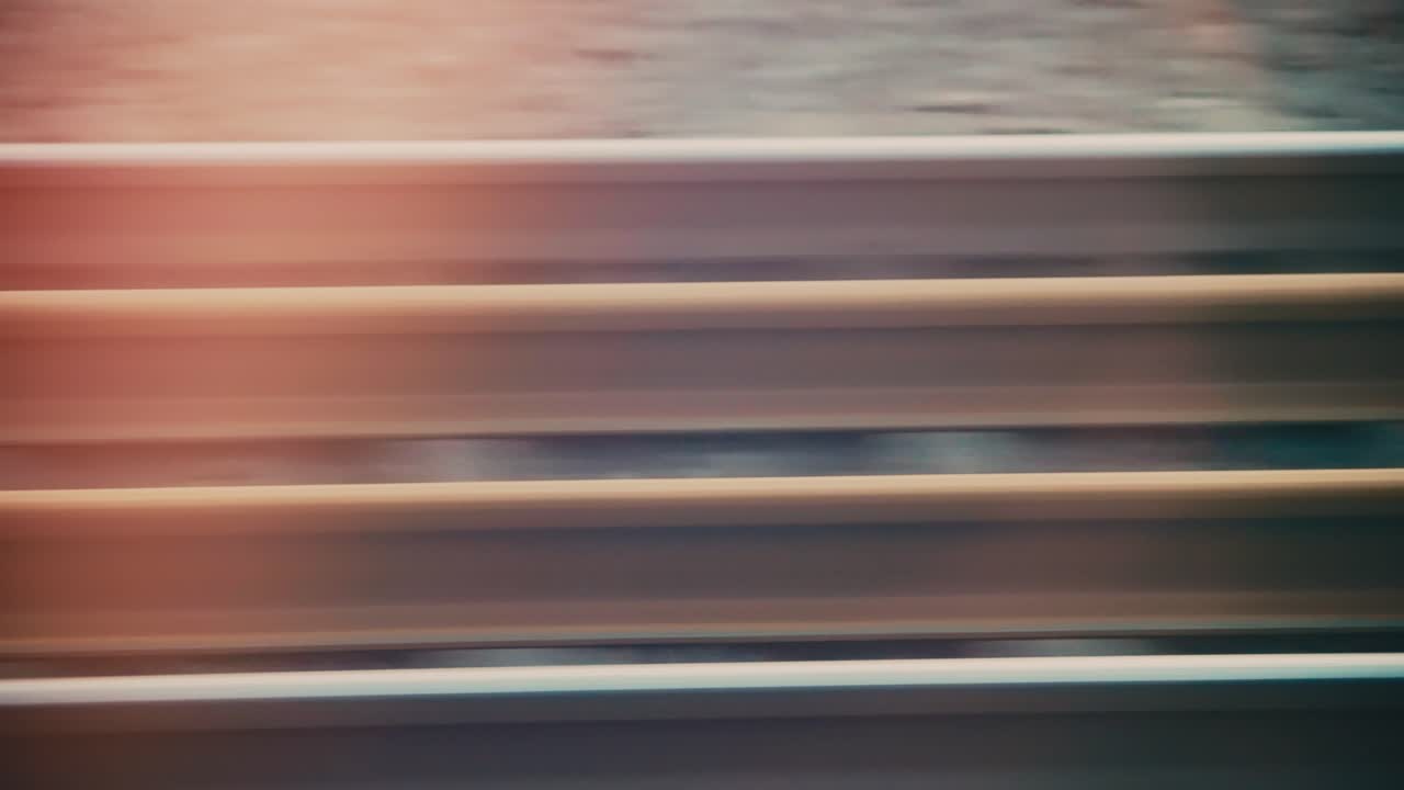Abstract POV through train window capturing rail tracks passing by in high speed, showcasing movement and urban landscapes
