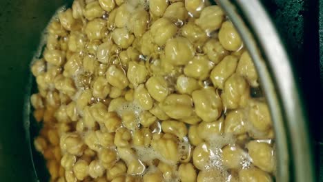 Vertical-close-up-view-of-a-pot-of-chickpeas-in-boiling-water-for-making-falafel,-candid-genuine-home-life-moment