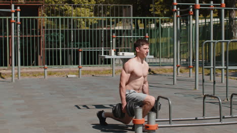 athletic caucasian muscular man doing exercises with weight squatting with dumbbells in hands