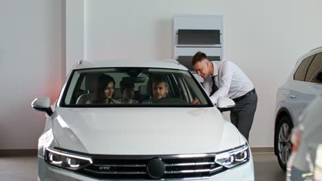 family at car dealership looking at a new car.