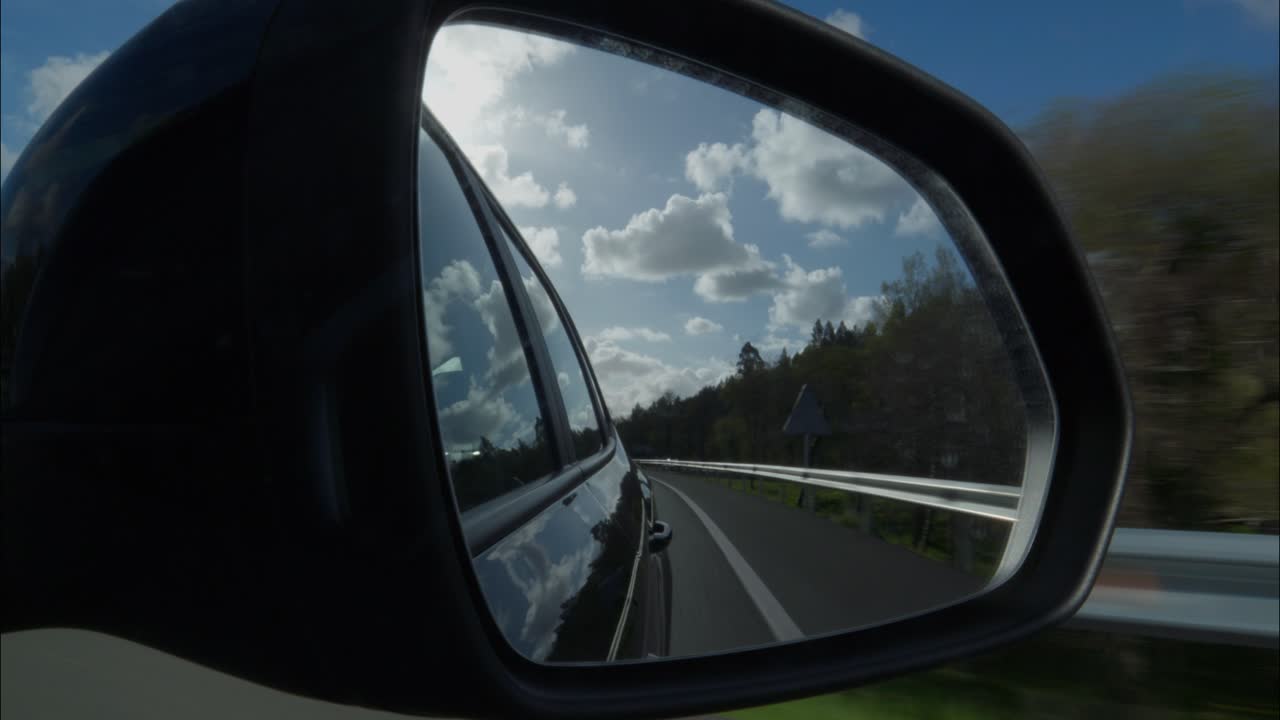 Vista dallo specchietto retrovisore laterale dell'auto mentre si guida in autostrada.