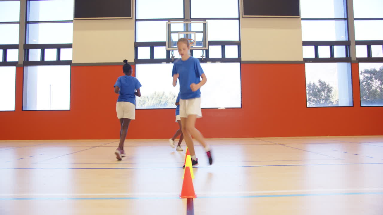 Running in gym, kids participating in school sports activity with cones