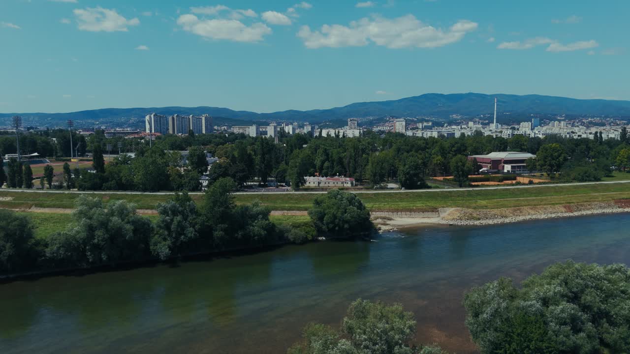 aerial - Sava River and Zagreb cityscape framed by mountains and skyline under summer sun