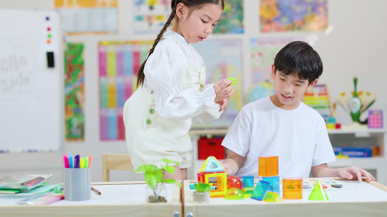 明るい教室で、2人の子供が協力してカラフルなブロックを組み立てている。チームワークと実践的な学びを育む様子。