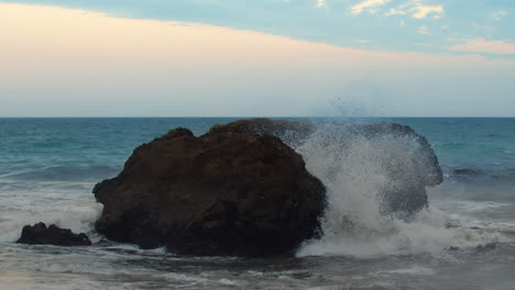 waves crashing on boulder