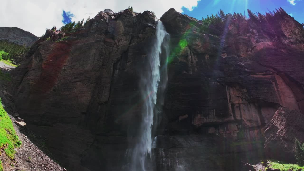 Summer green Telluride Bridal Veil Falls Waterfall Colorado powerplant house aerial drone Box Canyon Black Bear Pass Road Rocky Mountains 4wd hiking blue sky cliffs Uncompahgre Forest pan down motion