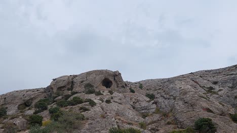 montaña de piedra rocosa, panorama desde abajo, gruta redonda, paisaje dramático.