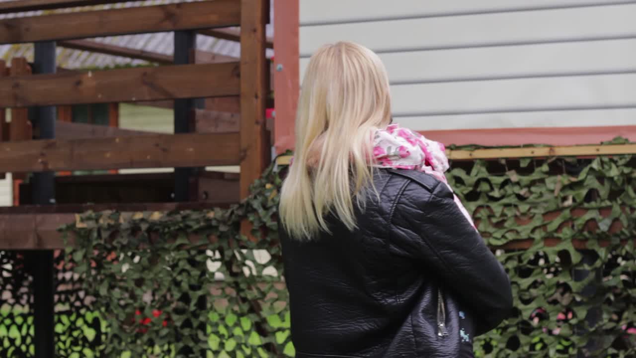 Adorable scene in exterior garden of European mom holding her sleepy African daughter, tired after playing outdoor, static, day