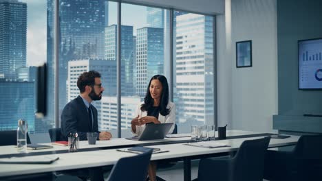 multi-ethnic businesspeople in modern office: asian businesswoman and caucasian businessmantalk. top manager and partner investor discuss e-commerce software investment strategy. static wide shot
