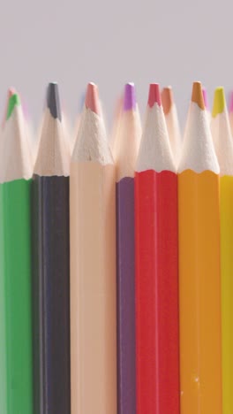 vertical video studio shot of rotating multi-coloured pencils against white background 2