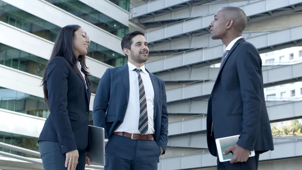 compañeros de trabajo con dispositivos digitales saludándose entre sí