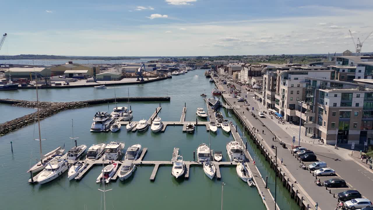 Poole Quay Marina. Low flight over marina and Town Quay towards lifting bridge showing marina and commercial docks on calm bright sunny day