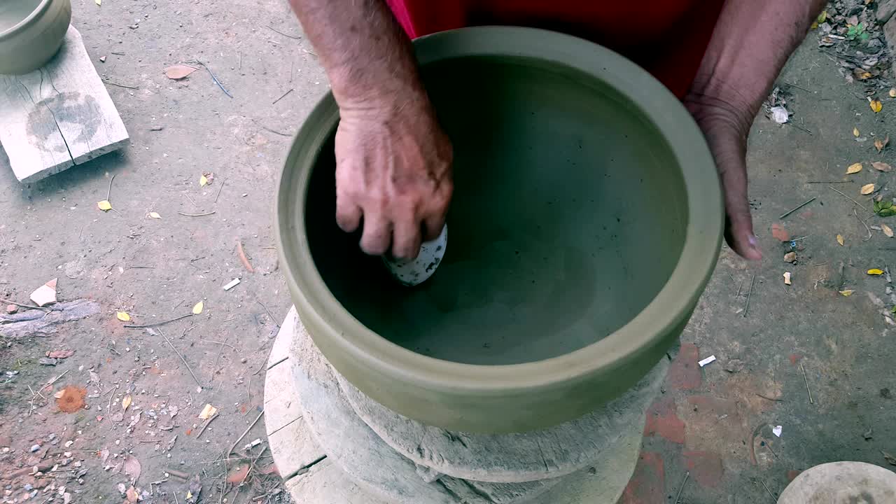 manos de hombre de primer plano pulir olla de arcilla con concha de mejillón de mar