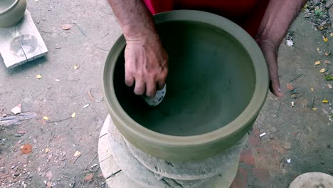 closeup man hands polish clay pot with sea mussel shell