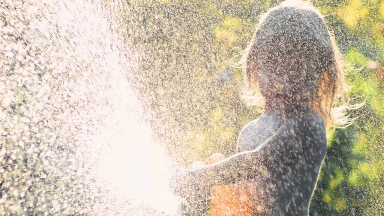 Child playing with water hose in summer