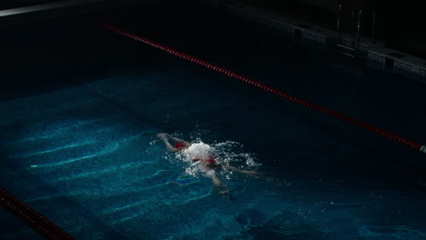 una mujer en un traje de baño rojo nadando en una piscina de competición