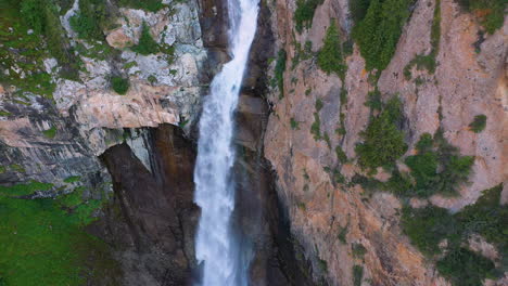 drone shot of barskoon waterfall in fairy tale canyon in kyrgyzstan, starting downward and then tilting to reveal falls, aerial footage